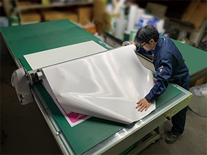 They stick sheets to the boards on a working table like this. When using the UV printer, the printed sheets are stiff and easy to handle.
