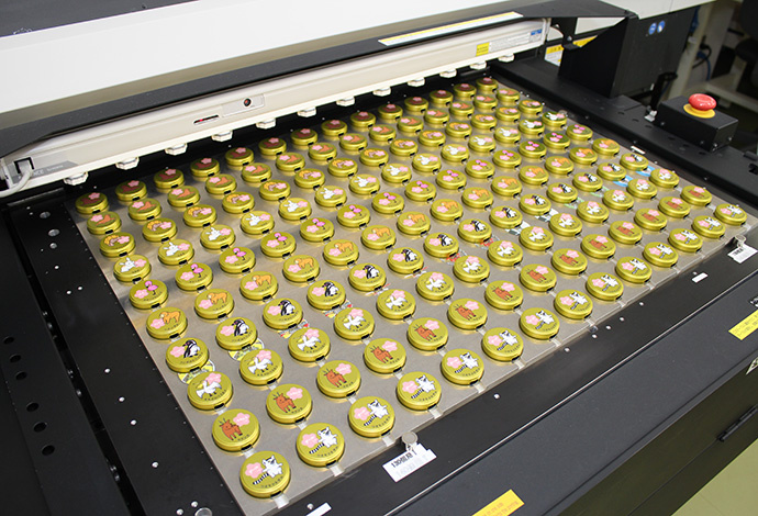 Printing on the lids arranged on the board with a special jig