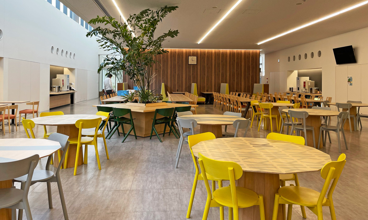 At the cafeteria of Karimoku Furniture, tables with a design printed on them are placed. The grains in the wood are still visible among the stylish design.